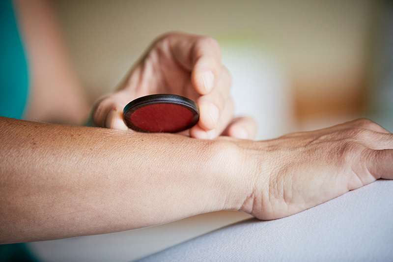 Eine Hand hält einen Redater, ein rotes Teil an einen Arm